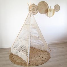 a white teepee sitting on top of a wooden floor next to two baskets hanging from the wall