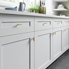 a kitchen with white cabinets and gold handles