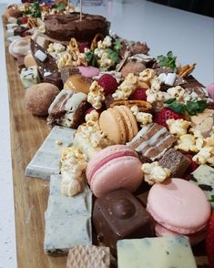 many different types of desserts are lined up on a long wooden table with chocolate, marshmallows and strawberries