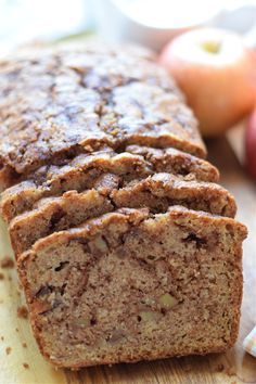 sliced loaf of banana bread sitting on top of a cutting board next to an apple