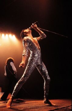 an image of a man that is on stage with a microphone and some people in the background