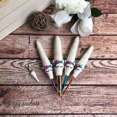 three pens with unicorn faces on them sitting next to some flowers and a pen holder