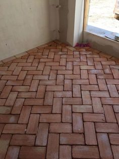 a brick floor in front of a window with a broom on the ground next to it