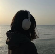 a person with headphones on looking out at the ocean