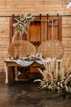 two wicker mirrors sitting on top of a table next to flowers and greenery