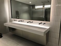 a bathroom with two sinks and a mirror above it in front of a wall mounted towel dispenser