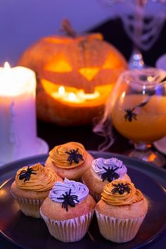 some cupcakes are on a plate with candles and pumpkins in the background