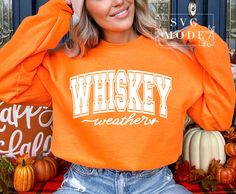 a woman wearing an orange whiskey sweatshirt and jeans