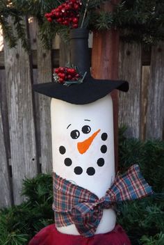 a snowman with a black hat and bow tie sitting in front of a fence