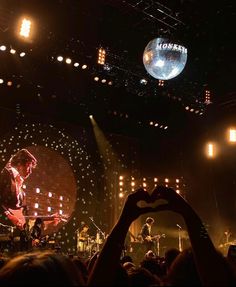 a person making a heart with their hands at a concert