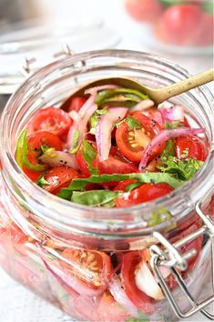 a jar filled with sliced tomatoes, onions and lettuce on top of a table