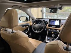 the interior of a car with beige leather seats and dashboards, including steering wheel