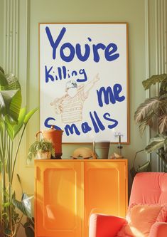 an orange chair sitting next to a yellow cabinet in front of a poster that says you're killing me smalls