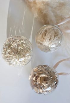 three glass vases filled with different types of crystals on a white surface next to feathers