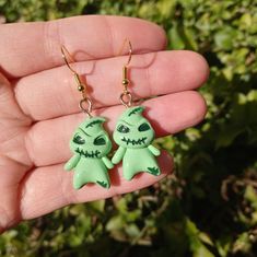 a pair of green monster earrings on a person's hand