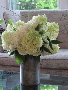 a vase filled with white flowers sitting on top of a table next to a couch