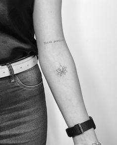 a woman's arm with a small flower tattoo on the left side of her arm