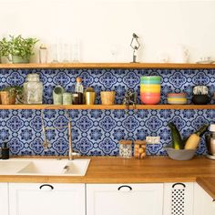 a kitchen with blue and white tiles on the wall, wooden counter tops and cabinets