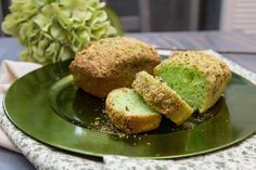 three pieces of bread on a green plate next to a vase with flowers in it