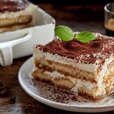 a piece of cake on a plate with a fork next to it and a cup of coffee in the background