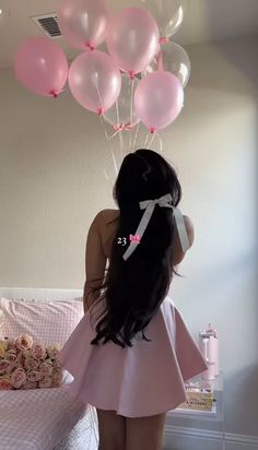 a woman standing in front of a bed with pink and white balloons