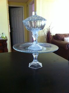 a glass cake plate sitting on top of a wooden table next to a brown couch