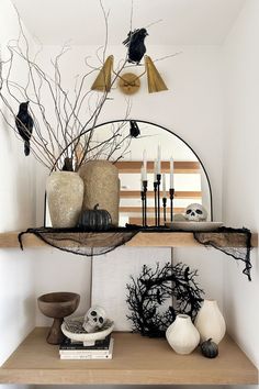 a table topped with vases filled with flowers and candles next to a mirror on top of a shelf