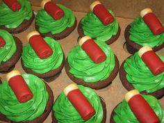 cupcakes with green frosting and red icing on top, in a cardboard box