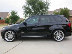 a black bmw suv parked in front of a house