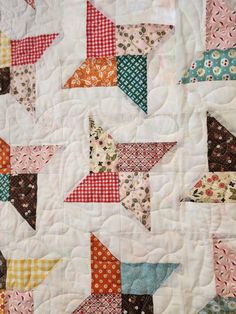 a close up of a quilt with many different colored stars on it