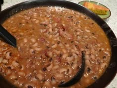 a black bowl filled with beans sitting on top of a counter next to a knife