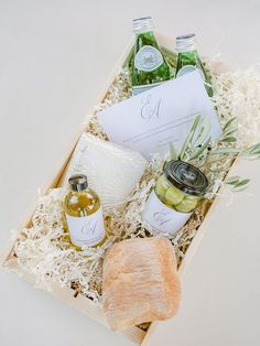 an open box containing olives, bread and personal care items for the bride to be