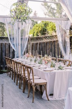 an outdoor dining table set up with white linens and flowers