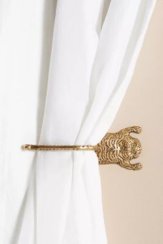 a white curtain with a gold lion head tie bar attached to it's side