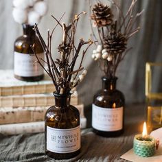 two bottles with flowers in them sitting on a table next to some books and candles