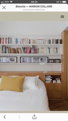 a bed sitting in front of a book shelf filled with books