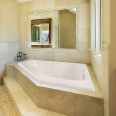 a bathroom with a large bathtub next to a walk in shower and two sinks