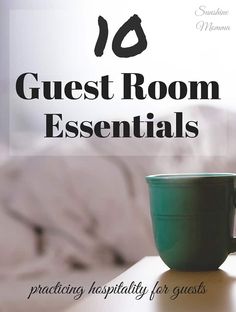 a green cup sitting on top of a wooden table next to a white bed with the words guest room essentials