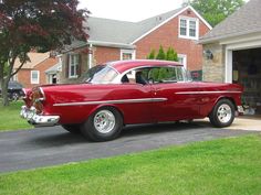 an old red car parked in front of a house