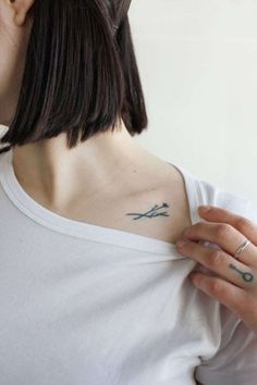 a woman with a small tattoo on her left shoulder and right arm holding scissors in one hand