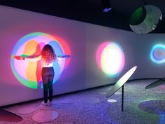 a woman is standing in front of colorful circles on the wall and pointing at it