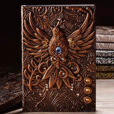 an intricately embossed leather book with blue eyes sits on a wooden table