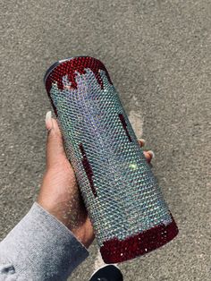 a person is holding a case with red and blue sequins on it while standing in the street