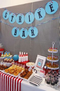 a table topped with lots of food next to a wall covered in striped paper decorations