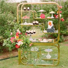 there is a cake stand with cupcakes on it and flowers in the background