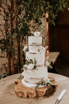 a wedding cake sitting on top of a wooden table next to a knife and fork