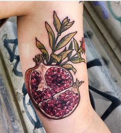 a pomegranate tattoo on the arm with leaves and berries in a vase