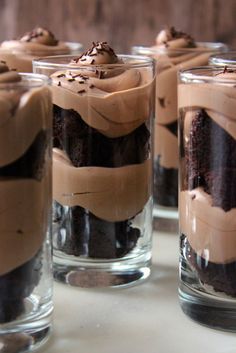 four glasses filled with desserts sitting on top of a table next to each other