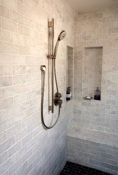 a walk in shower sitting next to a white brick wall