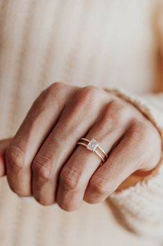 a woman's hand wearing a gold ring with a diamond on the middle finger